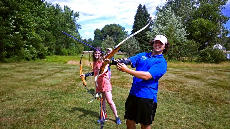 Two students hold up bows for an LL Bean discovery class on archery